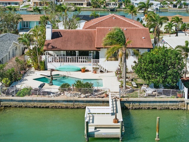 11285 8th St E, Treasure Island, FL 33706 - rear view of property featuring a tile roof, a water view, stucco siding, a residential view, and a chimney