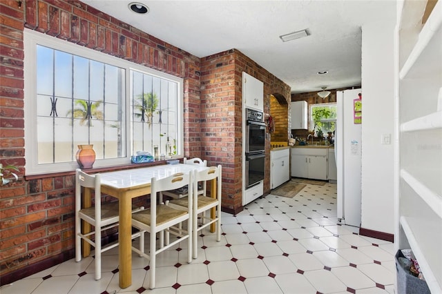 11285 8th St E, Treasure Island, FL 33706 - kitchen featuring light floors, brick wall, double oven, and freestanding refrigerator