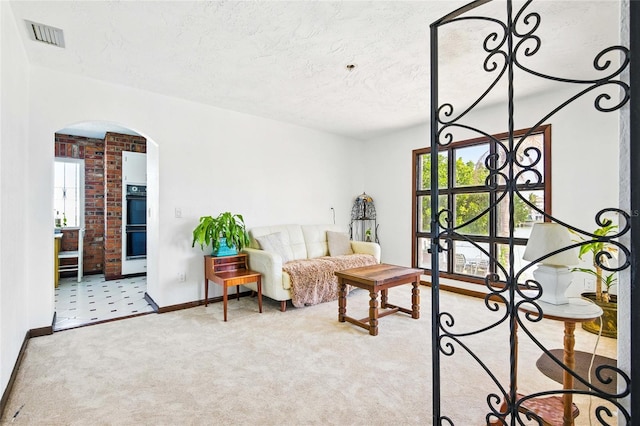 11285 8th St E, Treasure Island, FL 33706 - sitting room with arched walkways, baseboards, healthy amount of natural light, carpet, and a textured ceiling