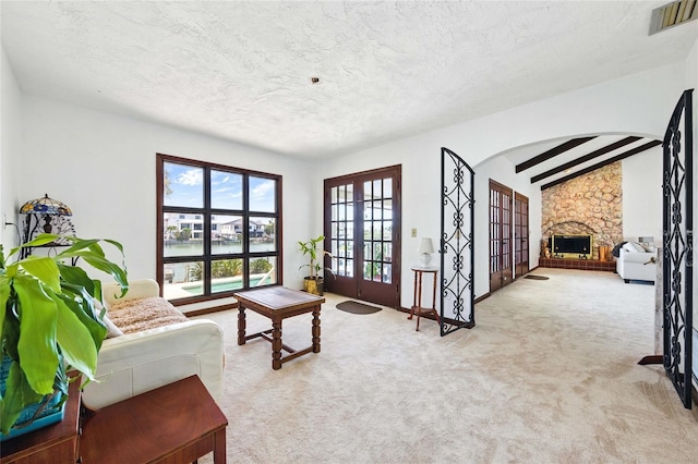 11285 8th St E, Treasure Island, FL 33706 - living room with french doors, carpet, a textured ceiling, a water view, and a stone fireplace