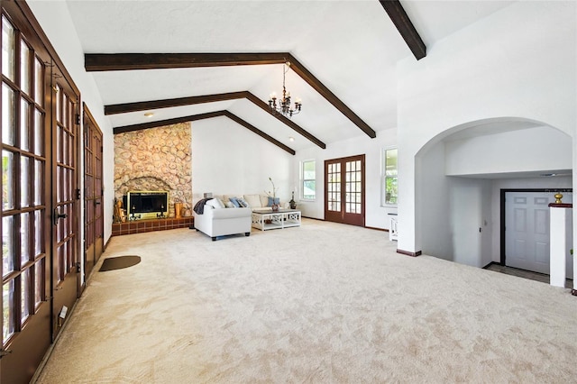 11285 8th St E, Treasure Island, FL 33706 - unfurnished living room with french doors, beam ceiling, carpet, a chandelier, and a stone fireplace