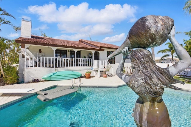 11285 8th St E, Treasure Island, FL 33706 - rear view of property with a tile roof, an outdoor pool, a patio area, stucco siding, and a chimney