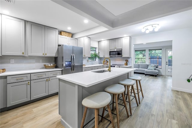 300 33rd Ave N, Saint Petersburg, FL 33704 - kitchen featuring appliances with stainless steel finishes, gray cabinetry, a sink, light wood-style flooring, and a breakfast bar area