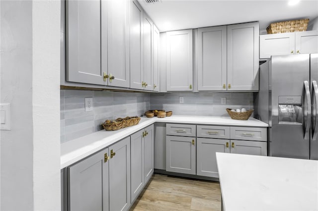 300 33rd Ave N, Saint Petersburg, FL 33704 - kitchen featuring stainless steel fridge, gray cabinets, light countertops, backsplash, and light wood-style flooring
