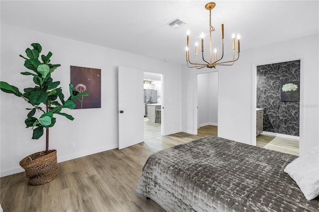 300 33rd Ave N, Saint Petersburg, FL 33704 - bedroom featuring a chandelier, wood finished floors, baseboards, stainless steel refrigerator with ice dispenser, and connected bathroom