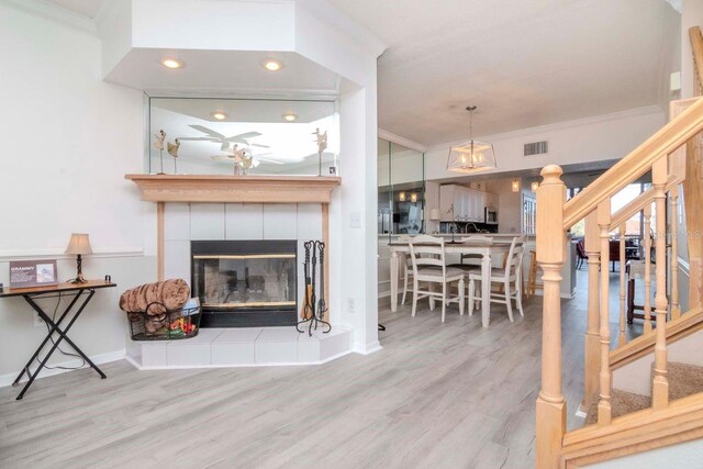 2648 Sabal Springs Dr Unit 2, Clearwater, FL 33761 - living area with ornamental molding, wood finished floors, a tile fireplace, a ceiling fan, and stairway