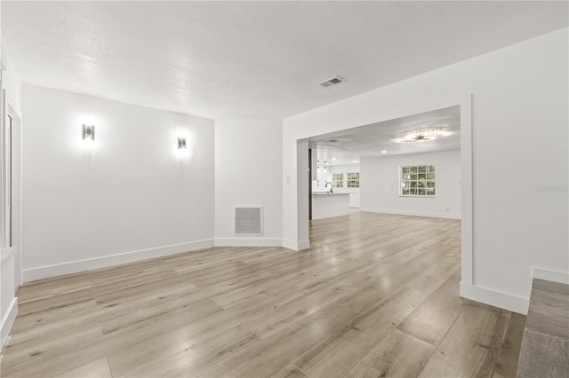 2554 Lake Ellen Cir, Tampa, FL 33618 - empty room with light wood-style flooring, a textured ceiling, and baseboards