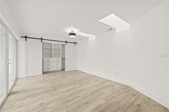 2554 Lake Ellen Cir, Tampa, FL 33618 - unfurnished bedroom featuring a barn door, light wood-style floors, and baseboards