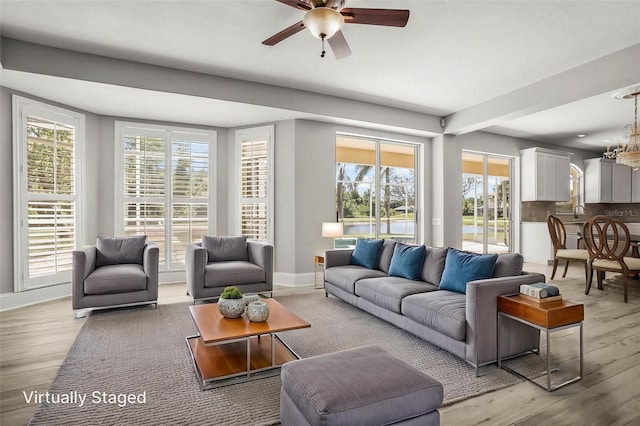 5160 Loquat Ct, Palm Harbor, FL 34685 - living room featuring light wood-type flooring, healthy amount of natural light, a ceiling fan, and baseboards