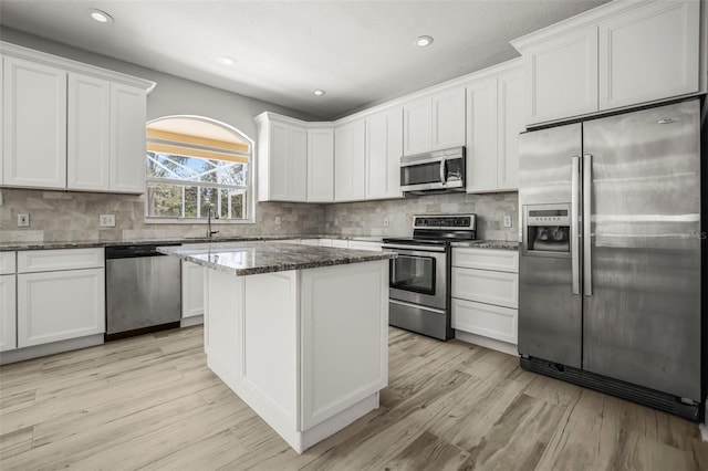5160 Loquat Ct, Palm Harbor, FL 34685 - kitchen with stainless steel appliances, light wood-style flooring, dark stone counters, a kitchen island, and backsplash