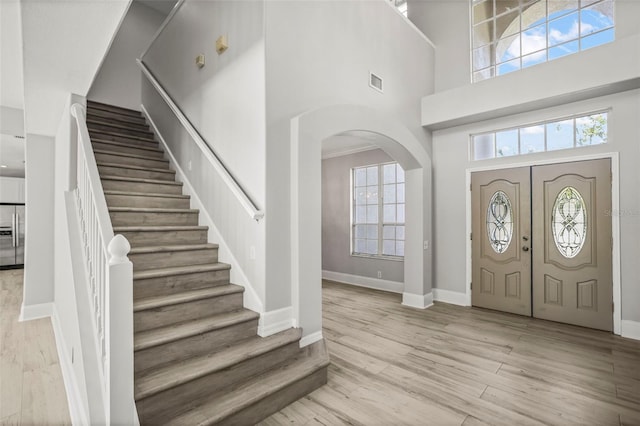 5160 Loquat Ct, Palm Harbor, FL 34685 - entrance foyer featuring a high ceiling, stairs, wood finished floors, arched walkways, and baseboards