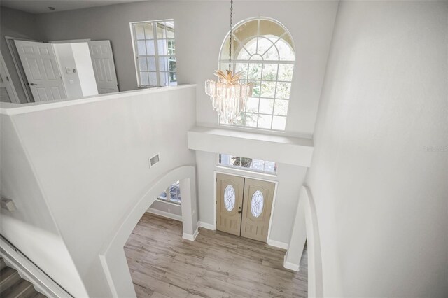 5160 Loquat Ct, Palm Harbor, FL 34685 - entrance foyer featuring a chandelier, arched walkways, wood finished floors, a towering ceiling, and baseboards