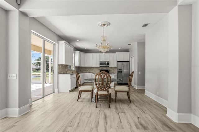 5160 Loquat Ct, Palm Harbor, FL 34685 - dining space featuring a chandelier, light wood-style flooring, and baseboards