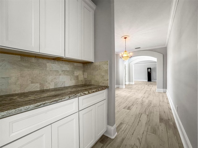 5160 Loquat Ct, Palm Harbor, FL 34685 - kitchen featuring arched walkways, decorative backsplash, light wood-type flooring, baseboards, and crown molding