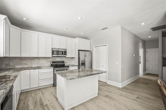 5160 Loquat Ct, Palm Harbor, FL 34685 - kitchen featuring stainless steel appliances, light wood finished floors, a kitchen island, tasteful backsplash, and light stone counters