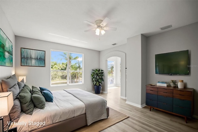 5160 Loquat Ct, Palm Harbor, FL 34685 - bedroom featuring arched walkways, light wood-style flooring, baseboards, and a ceiling fan