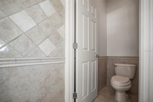 5160 Loquat Ct, Palm Harbor, FL 34685 - bathroom featuring toilet, tile patterned flooring, tile walls, and a wainscoted wall
