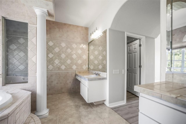 5160 Loquat Ct, Palm Harbor, FL 34685 - full bathroom with vanity, tile walls, decorative columns, a bath, and tile patterned floors