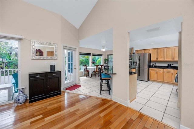 405 8th Ave N, Tierra Verde, FL 33715 - kitchen with stainless steel refrigerator with ice dispenser, dark countertops, light wood finished floors, light brown cabinetry, and high vaulted ceiling