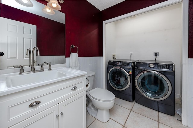 405 8th Ave N, Tierra Verde, FL 33715 - bathroom with washing machine and clothes dryer, vanity, tile patterned flooring, toilet, and a wainscoted wall
