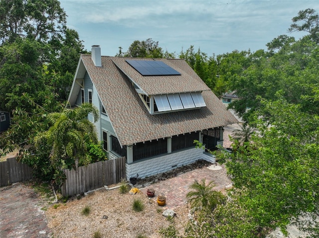 1825 2nd St S, Saint Petersburg, FL 33705 - view of front of house featuring a chimney, roof mounted solar panels, roof with shingles, and a sunroom