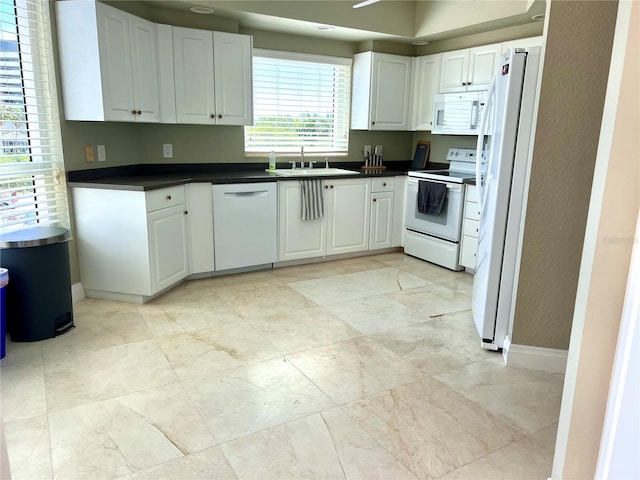 1180 Gulf Blvd Unit 306, Clearwater, FL 33767 - kitchen featuring white appliances, a sink, dark countertops, baseboards, and white cabinetry