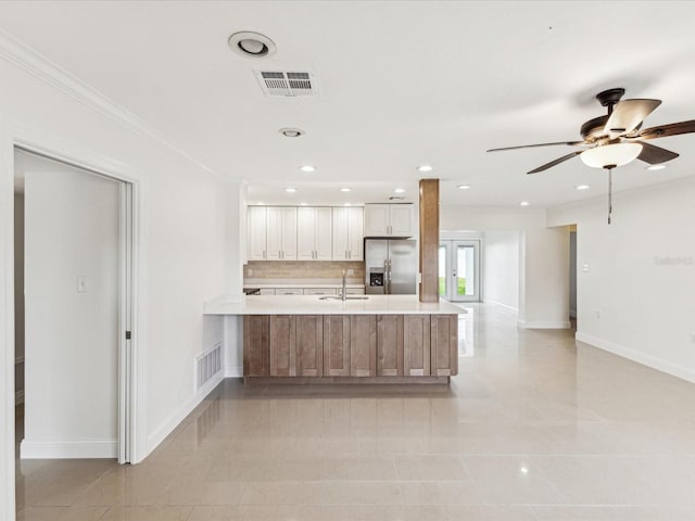 2016 Cove Dr, Largo, FL 33774 - kitchen with stainless steel fridge with ice dispenser, a peninsula, light countertops, a sink, and baseboards