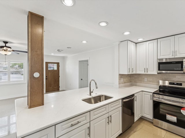 2016 Cove Dr, Largo, FL 33774 - kitchen featuring appliances with stainless steel finishes, a sink, ceiling fan, tasteful backsplash, and white cabinetry