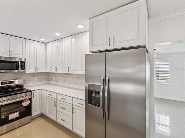 2016 Cove Dr, Largo, FL 33774 - kitchen featuring stainless steel appliances, light tile patterned flooring, ornamental molding, white cabinetry, and light countertops