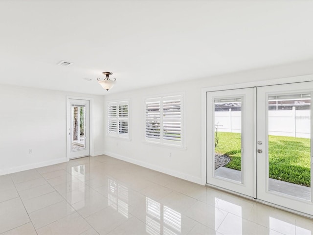 2016 Cove Dr, Largo, FL 33774 - empty room with healthy amount of natural light, light tile patterned floors, baseboards, and french doors