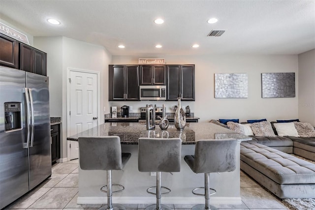 7030 Summer Holly Pl, Riverview, FL 33578 - kitchen featuring appliances with stainless steel finishes, open floor plan, a kitchen bar, dark stone counters, and recessed lighting