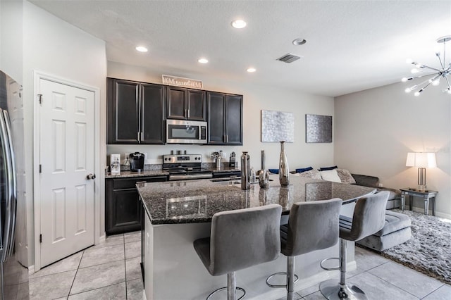 7030 Summer Holly Pl, Riverview, FL 33578 - kitchen with stainless steel appliances, open floor plan, a kitchen bar, dark stone countertops, and recessed lighting