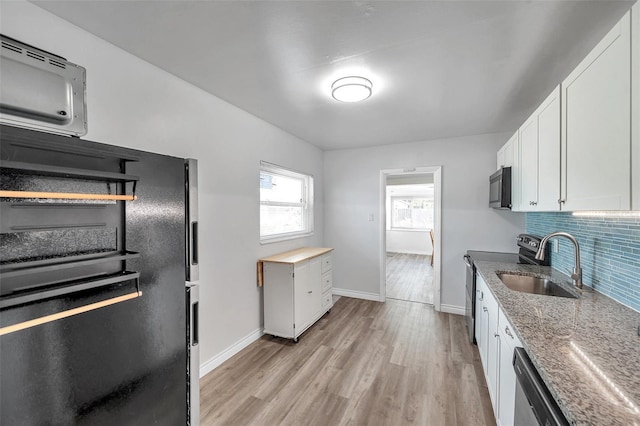 1117 Tyrone Blvd N, Saint Petersburg, FL 33710 - kitchen with appliances with stainless steel finishes, a sink, light wood-style flooring, white cabinets, and tasteful backsplash