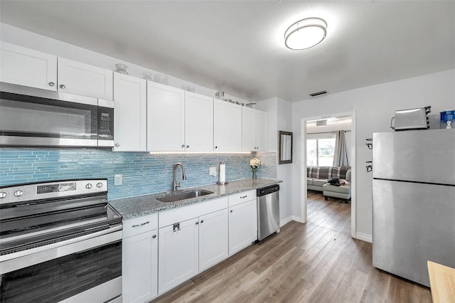 1117 Tyrone Blvd N, Saint Petersburg, FL 33710 - kitchen featuring stainless steel appliances, a sink, light wood-style floors, and white cabinets