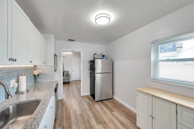 1117 Tyrone Blvd N, Saint Petersburg, FL 33710 - kitchen with freestanding refrigerator, a sink, decorative backsplash, light wood-style flooring, and white cabinetry