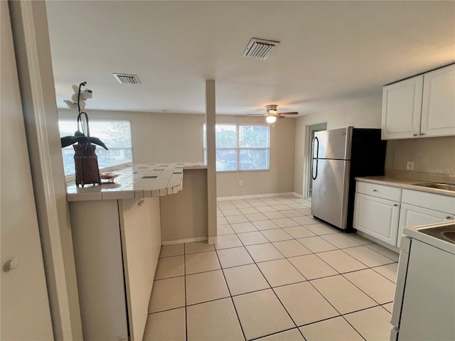 10367 109th Ave, Largo, FL 33773 - kitchen featuring electric stove, freestanding refrigerator, tile counters, a ceiling fan, and white cabinets