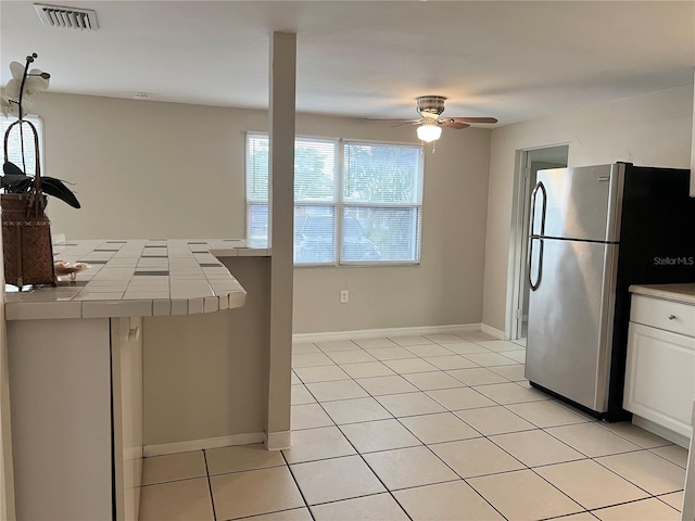 10367 109th Ave, Largo, FL 33773 - kitchen with tile counters, freestanding refrigerator, a ceiling fan, light tile patterned floors, and white cabinetry