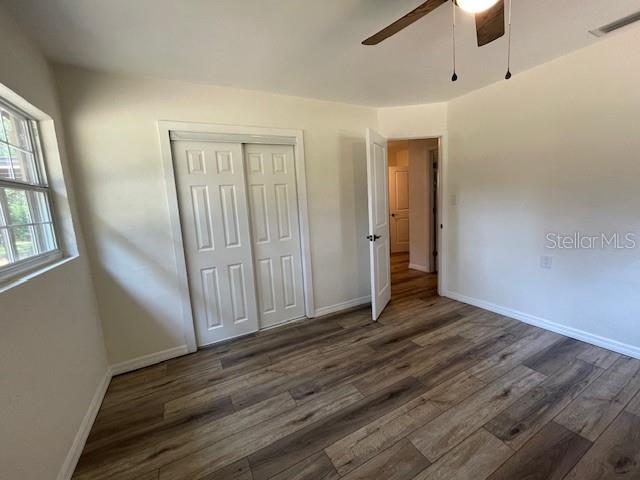 2748 Crk 543, Sumterville, FL 33585 - unfurnished bedroom with dark wood-style flooring, baseboards, a closet, and ceiling fan