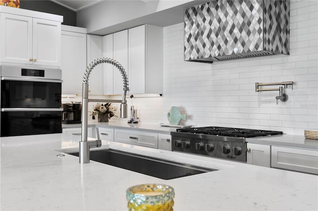 4649 Neptune Dr SE, Saint Petersburg, FL 33705 - kitchen featuring multiple ovens, tasteful backsplash, white cabinetry, wall chimney range hood, and ornamental molding