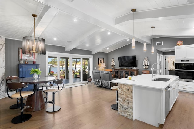4649 Neptune Dr SE, Saint Petersburg, FL 33705 - kitchen featuring a sink, light wood-style flooring, open floor plan, a chandelier, and white cabinets