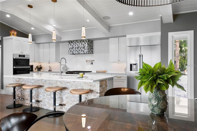 4649 Neptune Dr SE, Saint Petersburg, FL 33705 - kitchen featuring built in fridge, tasteful backsplash, a breakfast bar, beamed ceiling, and double wall oven