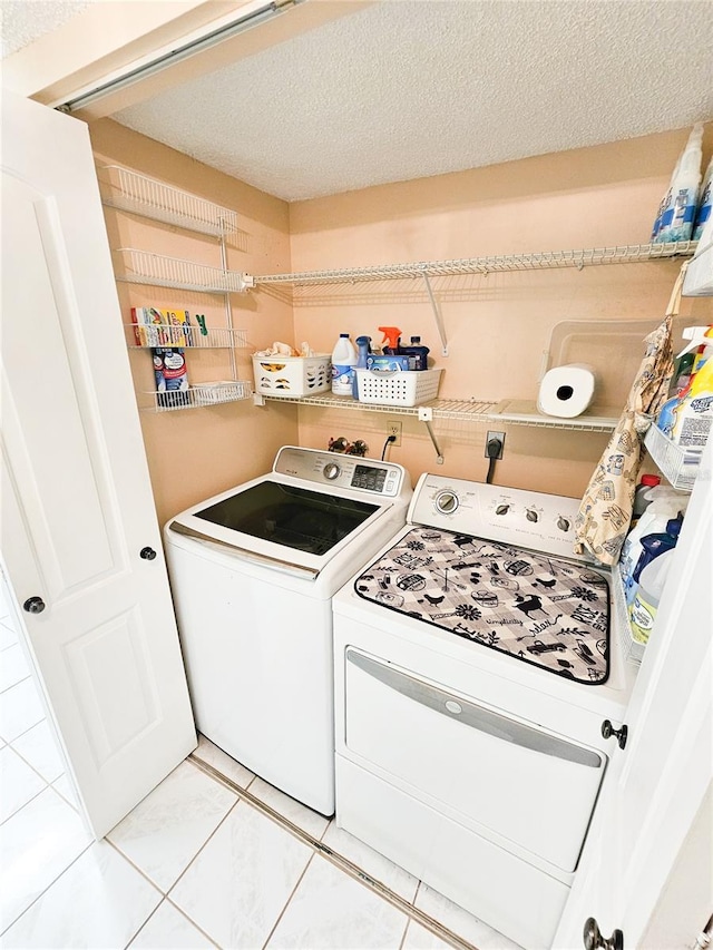 6060 Shore Dr S Unit 906, Gulfport, FL 33707 - laundry room featuring washing machine and clothes dryer, a textured ceiling, and light tile patterned floors