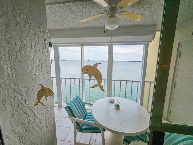 6060 Shore Dr S Unit 906, Gulfport, FL 33707 - dining space featuring a water view, ceiling fan, light tile patterned flooring, a textured ceiling, and plenty of natural light