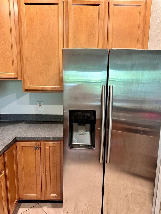 608 Black Lion Dr NE, Saint Petersburg, FL 33716 - kitchen with stainless steel fridge with ice dispenser, dark countertops, brown cabinets, and tile patterned floors