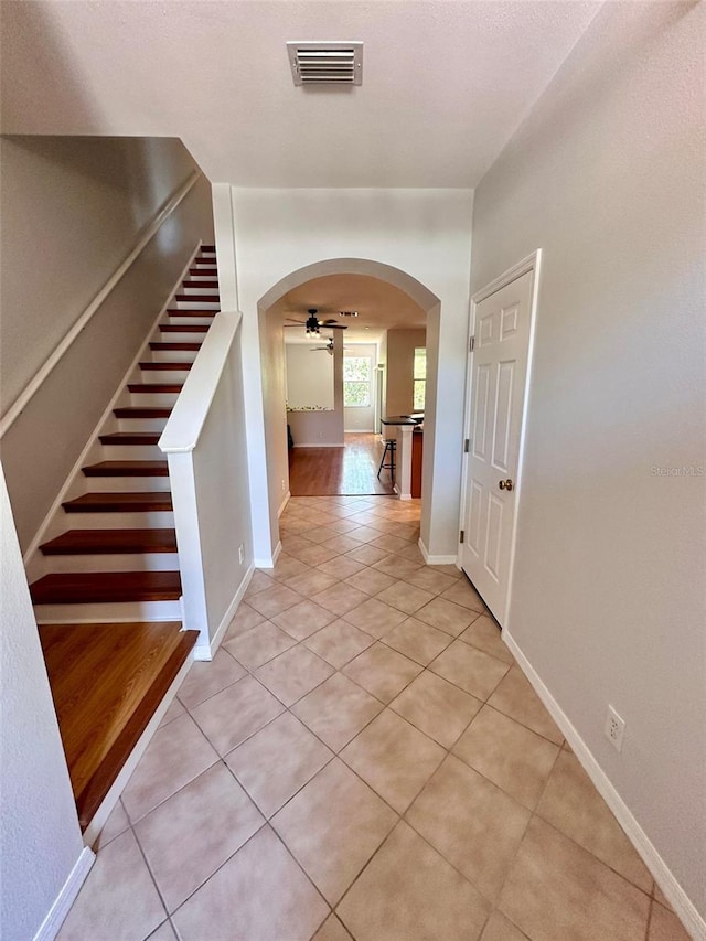608 Black Lion Dr NE, Saint Petersburg, FL 33716 - hall featuring arched walkways, light tile patterned floors, stairs, and baseboards