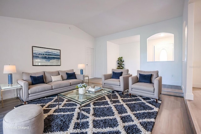 4260 Saint Lawrence Dr, New Port Richey, FL 34655 - living room with wood finished floors, lofted ceiling, arched walkways, and baseboards