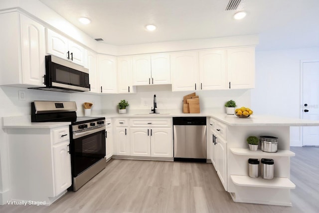 4260 Saint Lawrence Dr, New Port Richey, FL 34655 - kitchen featuring stainless steel appliances, a sink, open shelves, light wood-style flooring, and a peninsula