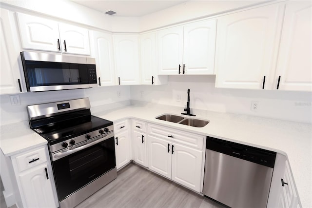 4260 Saint Lawrence Dr, New Port Richey, FL 34655 - kitchen featuring stainless steel appliances, a sink, white cabinets, light countertops, and light wood-type flooring