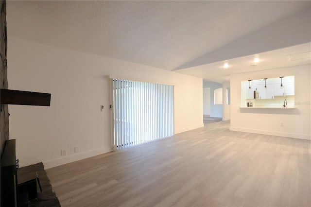 4260 Saint Lawrence Dr, New Port Richey, FL 34655 - unfurnished living room with light wood-type flooring, lofted ceiling, baseboards, and a sink