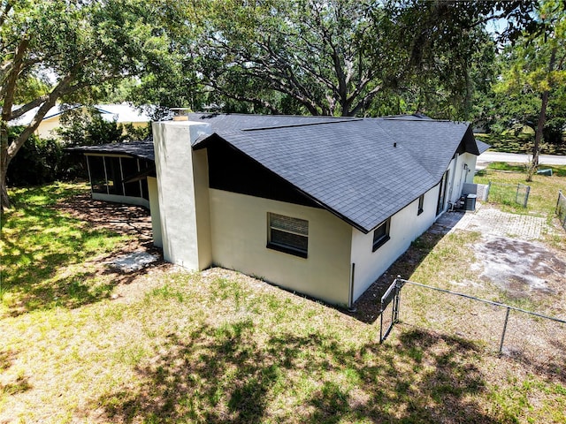 4260 Saint Lawrence Dr, New Port Richey, FL 34655 - view of side of home with roof with shingles, stucco siding, a chimney, a sunroom, and central AC unit